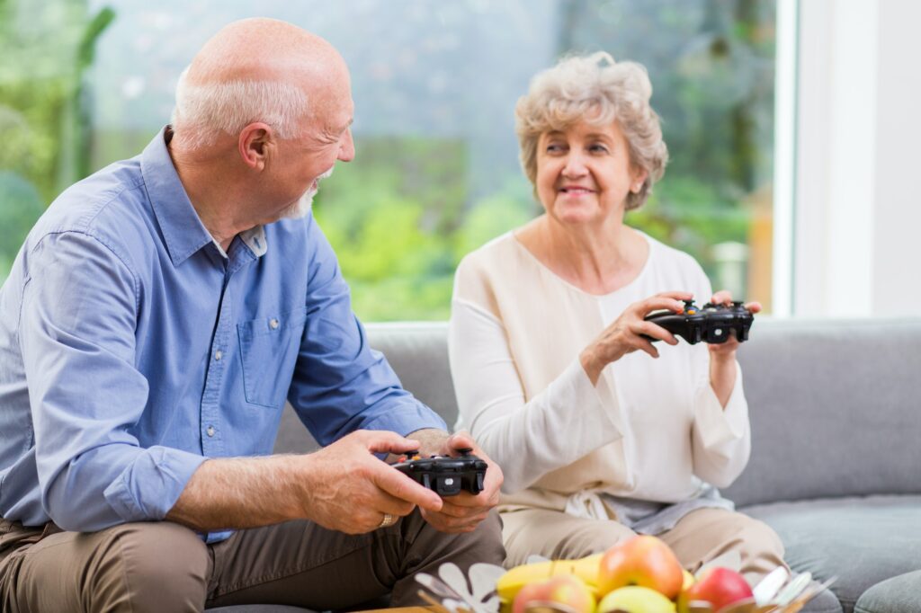 Grandmother and grandfather holding pads and playing video game